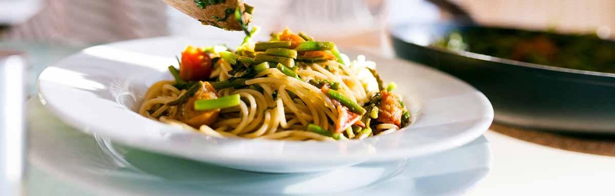 Una pasta italiana acompañada de verduras.