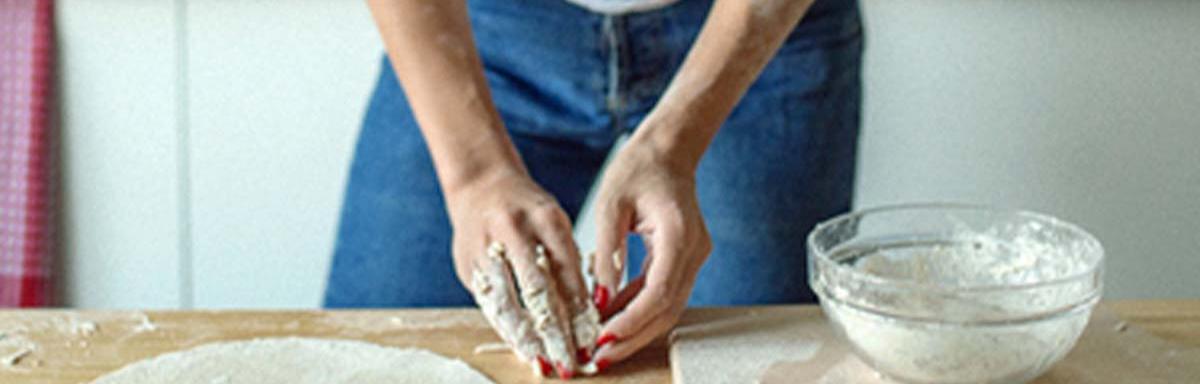 Mujer con utensilios e ingredientes preparando masa para pizza
