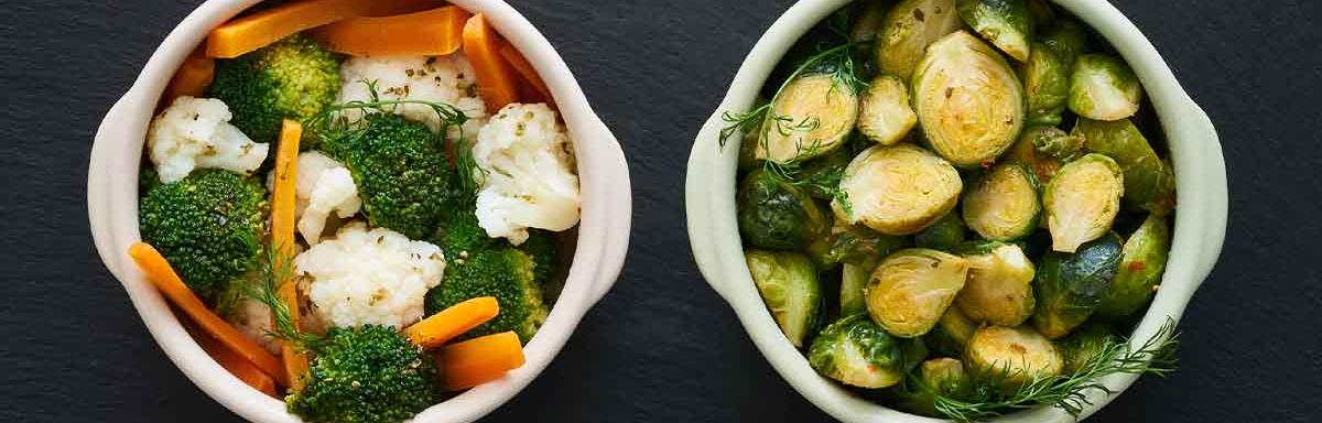 Zanahoria, brócoli y otras verduras que se suelen cocinar al vapor, servidas en dos tazas.