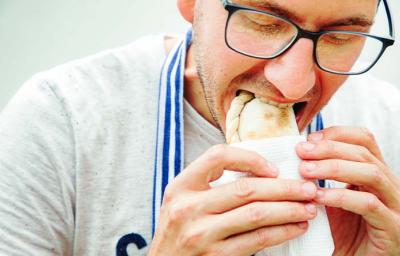 Un hombre comiendo una empanada tucumeña, una clase de empanada argentina.