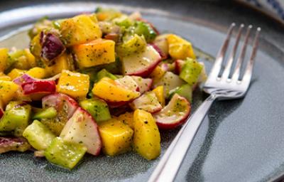 Una ensalada con mango y verduras, con su aderezo.