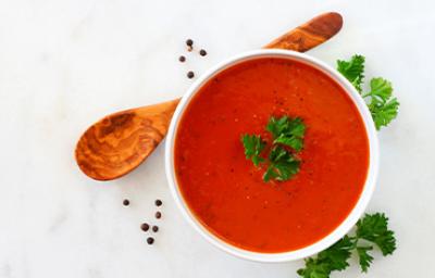 Crema de tomate con perejil, una de las recetas más famosas, servida con una cuchara de madera.