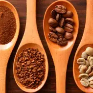 Cucharones de madera con café en polvo y grano